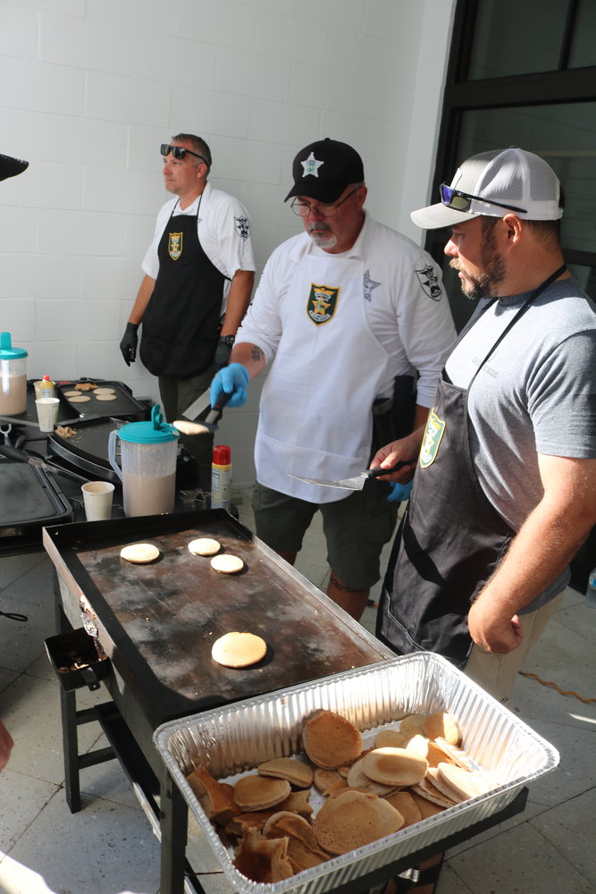 Members of the St. Johns County Sheriff’s Office prepare pancakes to be served. Their pancakes won the judges portion of the event’s contest.